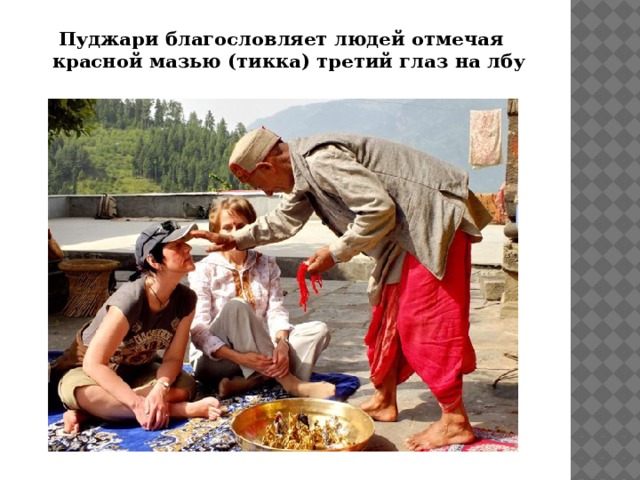 Пуджари благословляет людей отмечая красной мазью (тикка) третий глаз на лбу