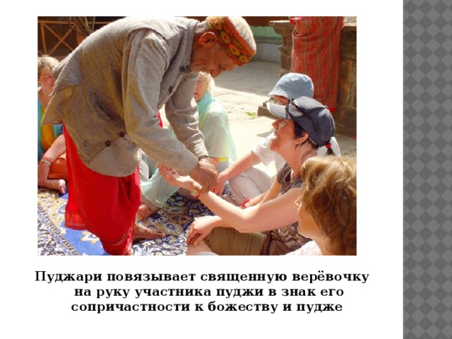 Пуджари повязывает священную верёвочку  на руку участника пуджи в знак его сопричастности к божеству и пудже