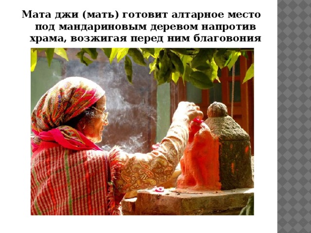 Мата джи (мать) готовит алтарное место под мандариновым деревом напротив храма, возжигая перед ним благовония