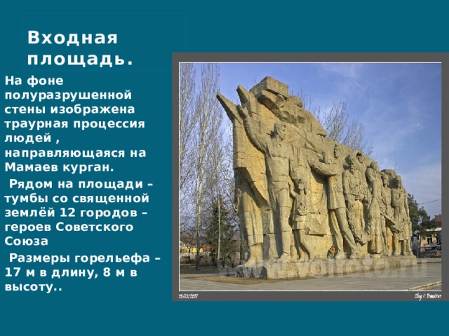 Входная площадь. На фоне полуразрушенной стены изображена траурная процессия людей , направляющаяся на Мамаев курган.  Рядом на площади – тумбы со священной землёй 12 городов – героев Советского Союза  Размеры горельефа – 17 м в длину, 8 м в высоту.. 
