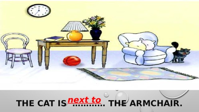 next to  The cat is ………… the armchair. 