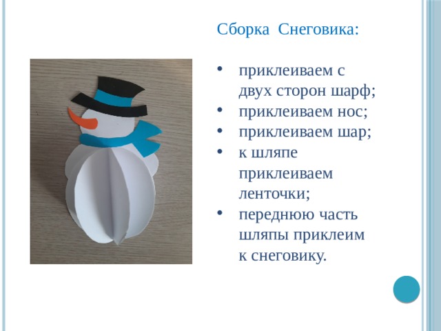Сборка Снеговика: приклеиваем с двух сторон шарф; приклеиваем нос; приклеиваем шар; к шляпе приклеиваем ленточки; переднюю часть шляпы приклеим к снеговику. 
