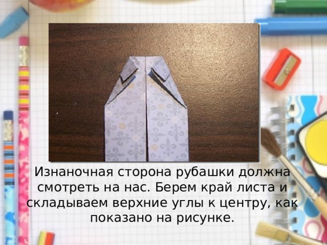 Изнаночная сторона рубашки должна смотреть на нас. Берем край листа и складываем верхние углы к центру, как показано на рисунке. 